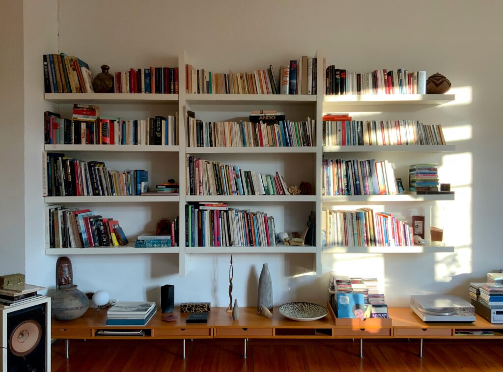 pexels-photo-32024218-32024218 Warm and inviting home library featuring sunlit, filled bookshelves and decorative items.